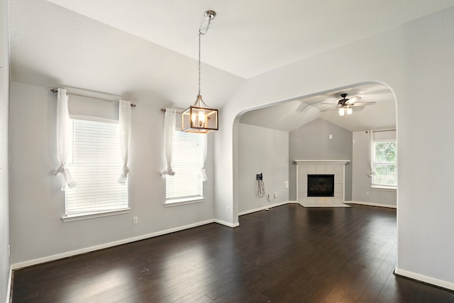 303 Burris Park Dr, Spring, TX 77373 - unfurnished living room with vaulted ceiling, arched walkways, a ceiling fan, dark wood-type flooring, and a fireplace