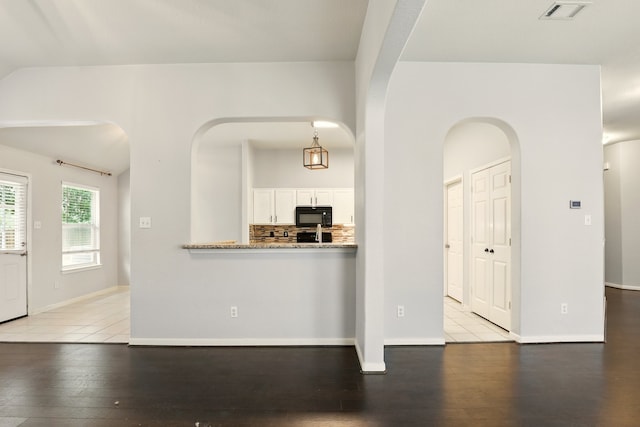 303 Burris Park Dr, Spring, TX 77373 - kitchen with black microwave, light wood-style flooring, white cabinetry, and arched walkways