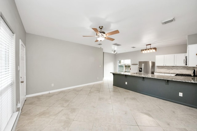 2214 Naomi St, Houston, TX 77054 - kitchen featuring stainless steel fridge, a ceiling fan, a breakfast bar, light stone countertops, and light tile patterned floors