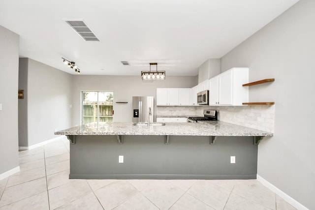 2214 Naomi St, Houston, TX 77054 - kitchen featuring stainless steel appliances, a peninsula, open shelves, decorative backsplash, and light stone countertops