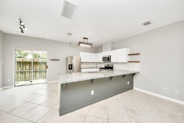 2214 Naomi St, Houston, TX 77054 - kitchen featuring appliances with stainless steel finishes, a peninsula, light tile patterned flooring, open shelves, and white cabinets