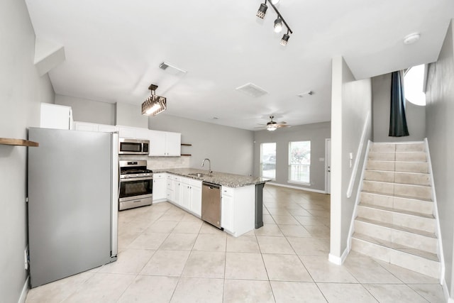 2214 Naomi St, Houston, TX 77054 - kitchen with appliances with stainless steel finishes, a peninsula, light tile patterned floors, light stone counters, and white cabinets