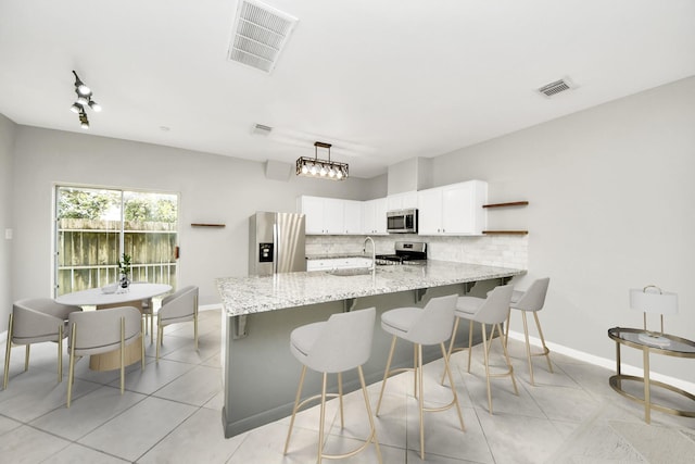 2214 Naomi St, Houston, TX 77054 - kitchen featuring appliances with stainless steel finishes, backsplash, light tile patterned floors, white cabinets, and a kitchen bar