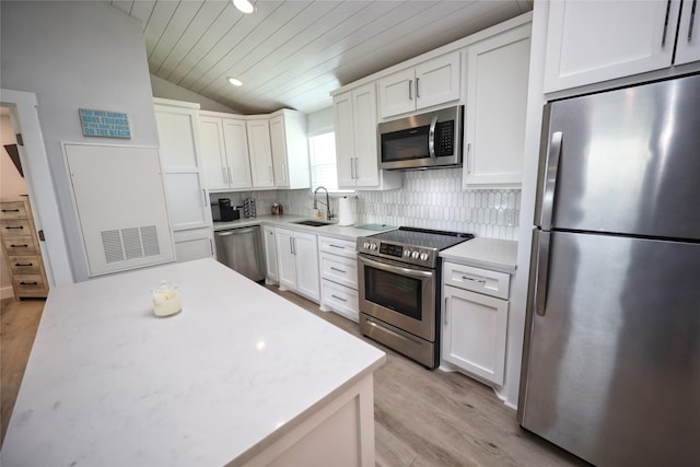 4022 3rd St, Galveston, TX 77554 - kitchen with stainless steel appliances, vaulted ceiling, white cabinets, light countertops, and tasteful backsplash
