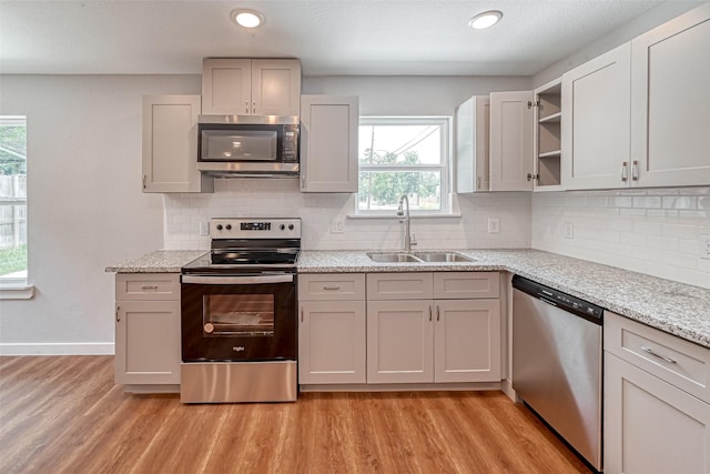 8125 Eastover St Unit Ab, Houston, TX 77028 - kitchen featuring appliances with stainless steel finishes, open shelves, light wood-type flooring, plenty of natural light, and recessed lighting
