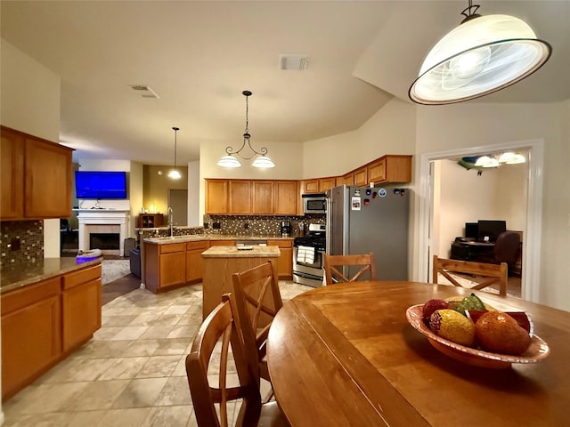 913 S Belle Dr, Angleton, TX 77515 - kitchen with appliances with stainless steel finishes, tasteful backsplash, brown cabinetry, and a fireplace