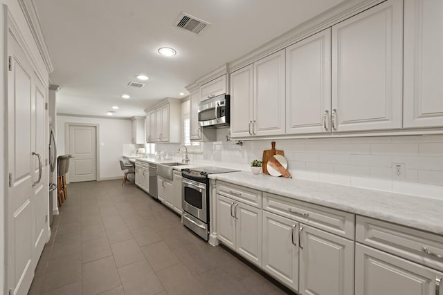 5743 Braesheather Dr, Houston, TX 77096 - kitchen featuring appliances with stainless steel finishes, white cabinetry, recessed lighting, backsplash, and dark tile patterned floors
