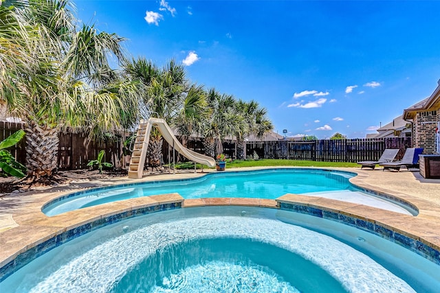20910 Cordell Landing Dr, Richmond, TX 77407 - view of pool with a water slide, a pool with connected hot tub, a fenced backyard, and a patio area
