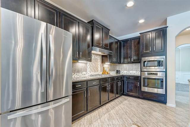 20910 Cordell Landing Dr, Richmond, TX 77407 - kitchen with appliances with stainless steel finishes, arched walkways, light stone counters, under cabinet range hood, and recessed lighting