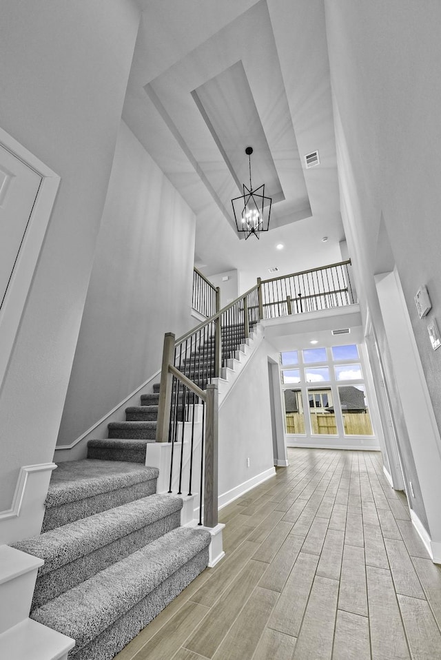 3244 Stingray Cove Dr, Katy, TX 77493 - stairway with a raised ceiling, a chandelier, a high ceiling, and wood finished floors