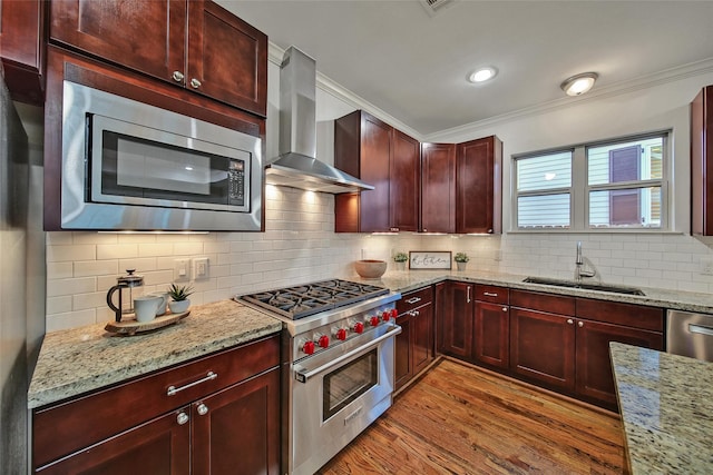 1822 Gardenia Dr, Houston, TX 77018 - kitchen featuring stainless steel appliances, wall chimney exhaust hood, reddish brown cabinets, crown molding, and light wood finished floors