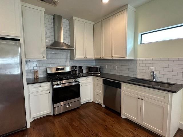 4730 Bell St, Houston, TX 77023 - kitchen featuring stainless steel appliances, wall chimney range hood, dark countertops, and recessed lighting