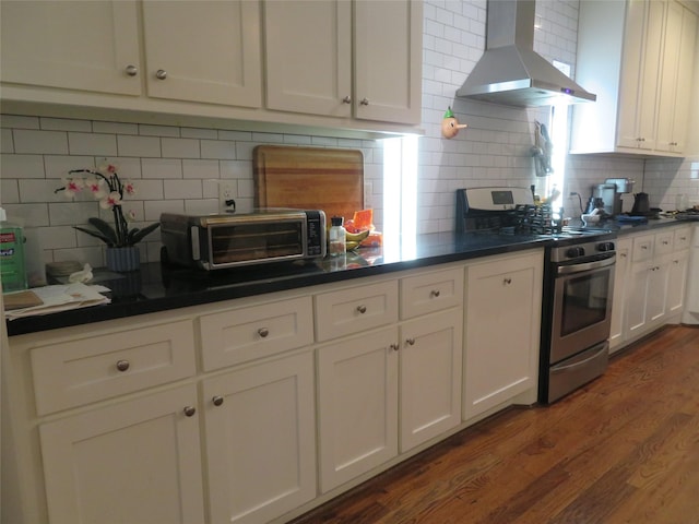 4730 Bell St, Houston, TX 77023 - kitchen with stainless steel gas range, island range hood, dark wood-type flooring, decorative backsplash, and dark countertops