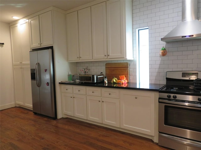 4730 Bell St, Houston, TX 77023 - kitchen featuring appliances with stainless steel finishes, wall chimney range hood, decorative backsplash, dark wood-style floors, and white cabinets
