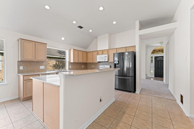 1627 Pebble Brk, Missouri City, TX 77459 - kitchen with stainless steel refrigerator with ice dispenser, lofted ceiling, light tile patterned flooring, white microwave, and light brown cabinets