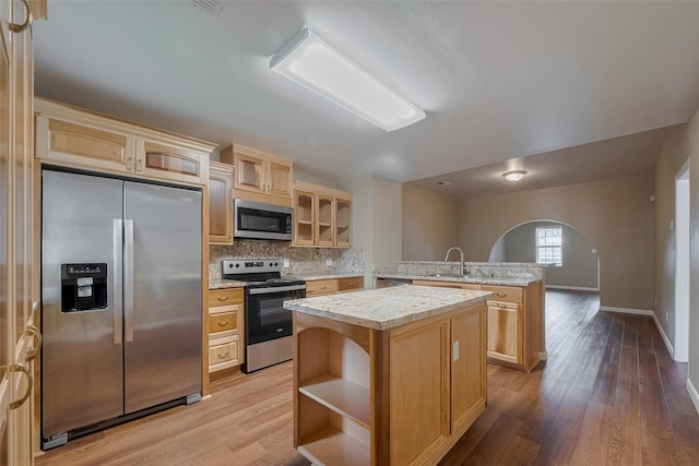 4519 N Main St, Houston, TX 77009 - kitchen with appliances with stainless steel finishes, a kitchen island, arched walkways, and light wood-type flooring