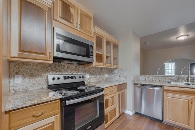 4519 N Main St, Houston, TX 77009 - kitchen with stainless steel appliances, light wood-style flooring, tasteful backsplash, glass insert cabinets, and light stone counters