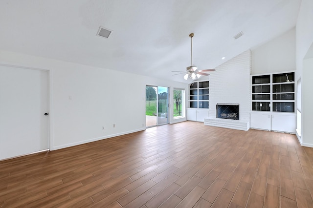 20031 Sunny Shores Dr, Humble, TX 77346 - unfurnished living room featuring ceiling fan, vaulted ceiling, wood finished floors, built in shelves, and a brick fireplace
