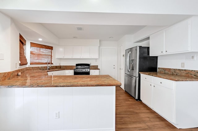 20031 Sunny Shores Dr, Humble, TX 77346 - kitchen featuring appliances with stainless steel finishes, a peninsula, wood finished floors, white cabinetry, and recessed lighting