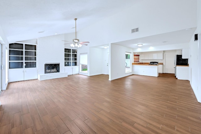 20031 Sunny Shores Dr, Humble, TX 77346 - unfurnished living room with ceiling fan, dark wood-style flooring, built in shelves, a brick fireplace, and high vaulted ceiling