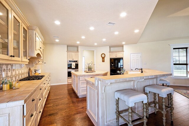 34210 Sanders Ranch Rd, Magnolia, TX 77355 - kitchen featuring a kitchen island with sink, double oven, tile counters, gas stovetop, and freestanding refrigerator
