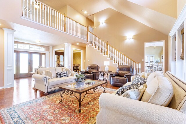 34210 Sanders Ranch Rd, Magnolia, TX 77355 - living area with ornate columns, stairs, high vaulted ceiling, and wood finished floors