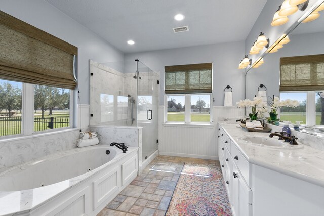 34210 Sanders Ranch Rd, Magnolia, TX 77355 - bathroom featuring double vanity, a tub with jets, a shower stall, stone tile flooring, and a wainscoted wall