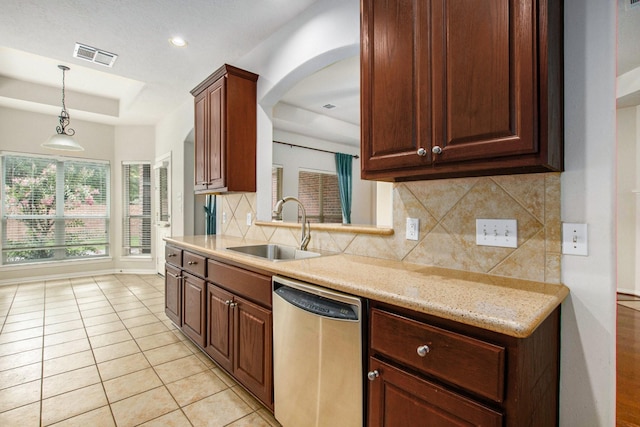 24006 Northshire Ln, Katy, TX 77494 - kitchen featuring stainless steel dishwasher, a raised ceiling, backsplash, arched walkways, and pendant lighting