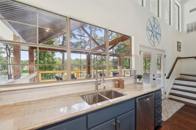 243 Riverbirch, Brookeland, TX 75931 - kitchen featuring blue cabinets, stainless steel dishwasher, a towering ceiling, dark wood-style flooring, and light stone countertops