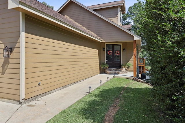 243 Riverbirch, Brookeland, TX 75931 - view of exterior entry featuring a yard, french doors, and a shingled roof