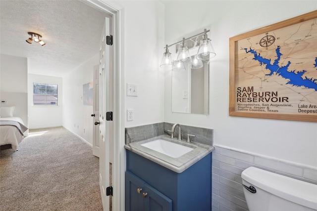 243 Riverbirch, Brookeland, TX 75931 - bathroom with vanity, a textured ceiling, and a wainscoted wall