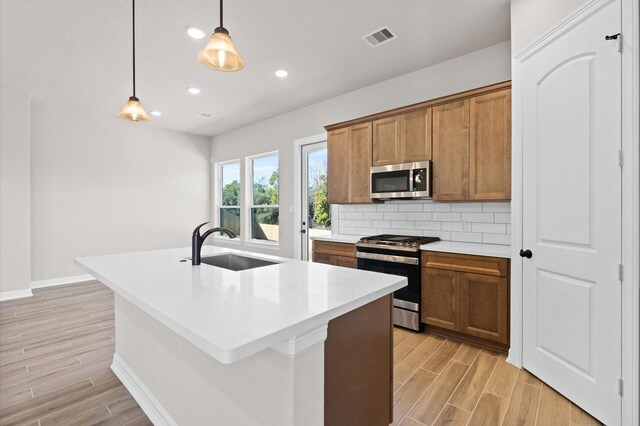 1613 Carefree Cir, Seabrook, TX 77586 - kitchen featuring stainless steel appliances, light wood-style floors, brown cabinets, tasteful backsplash, and light countertops