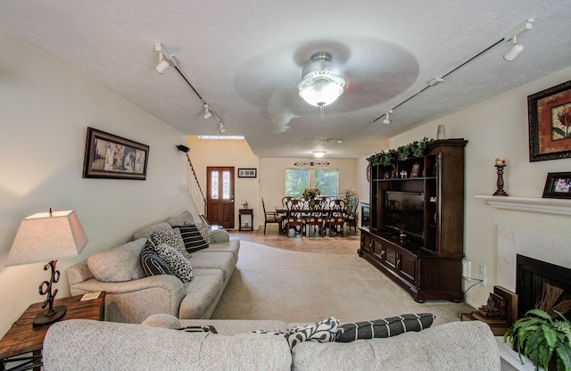 1010 Forestburg Dr, Spring, TX 77386 - living room with rail lighting, light carpet, stairway, a textured ceiling, and a premium fireplace