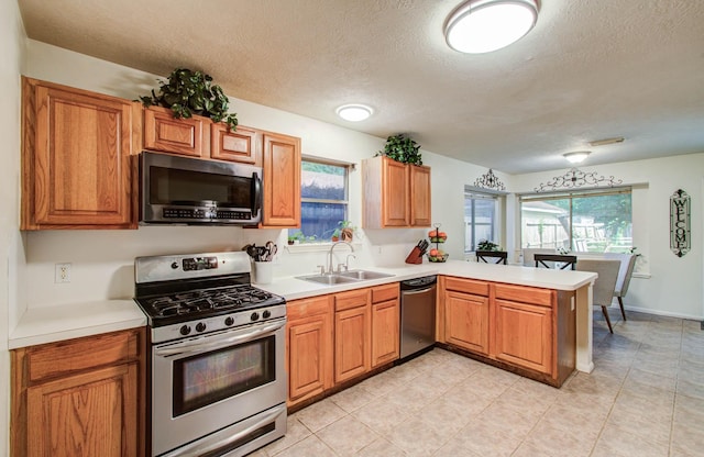 1010 Forestburg Dr, Spring, TX 77386 - kitchen featuring stainless steel appliances, a peninsula, a textured ceiling, light countertops, and healthy amount of natural light