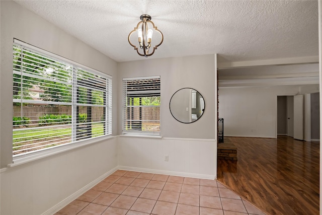 8214 Camborne Ln, Houston, TX 77070 - empty room with a chandelier, a textured ceiling, a wainscoted wall, and light wood-style floors