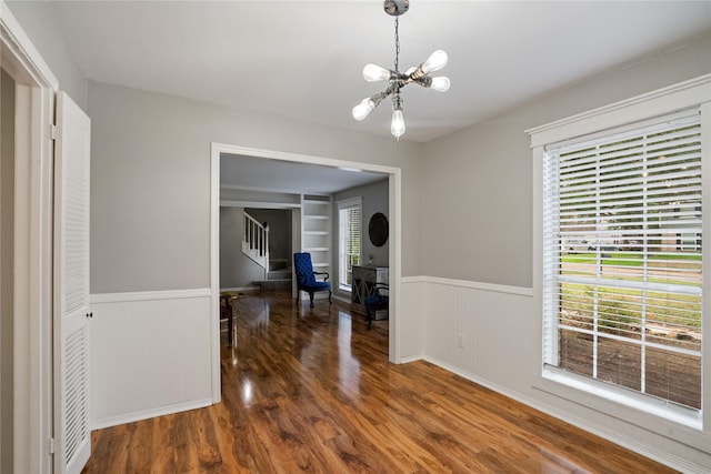 8214 Camborne Ln, Houston, TX 77070 - dining space featuring a chandelier, wainscoting, built in shelves, wood finished floors, and stairs
