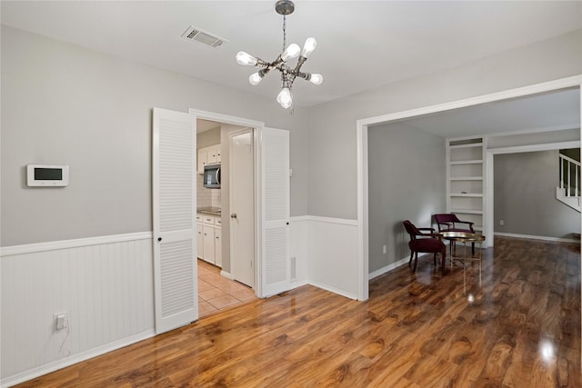 8214 Camborne Ln, Houston, TX 77070 - empty room featuring light wood-type flooring, a chandelier, wainscoting, built in features, and stairway