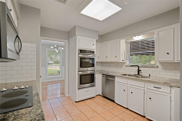 8214 Camborne Ln, Houston, TX 77070 - kitchen featuring stainless steel appliances, white cabinetry, backsplash, and light tile patterned floors