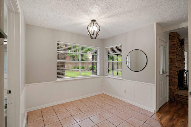 8214 Camborne Ln, Houston, TX 77070 - empty room with a chandelier, wainscoting, a textured ceiling, and light tile patterned floors