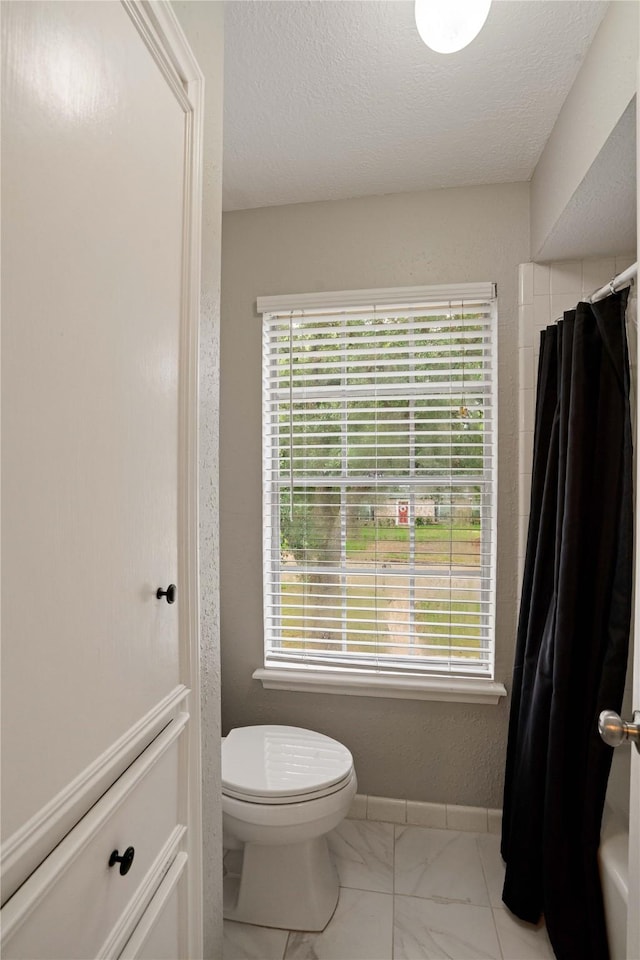 8214 Camborne Ln, Houston, TX 77070 - full bathroom with marble look tiles, a shower with shower curtain, and a textured ceiling