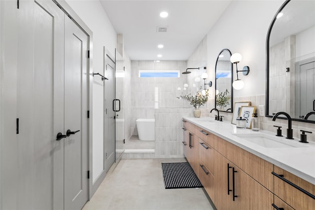 2948 Pitzlin St, Houston, TX 77023 - bathroom with double vanity, a soaking tub, a stall shower, tile patterned flooring, and tile walls