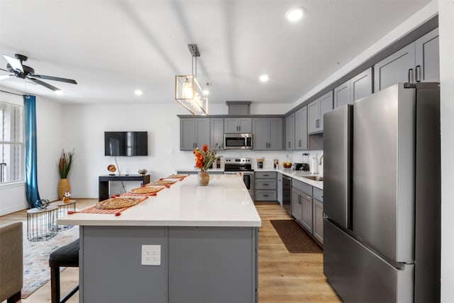 5214 Sherman St, Houston, TX 77011 - kitchen featuring appliances with stainless steel finishes, gray cabinetry, a center island, recessed lighting, and light countertops