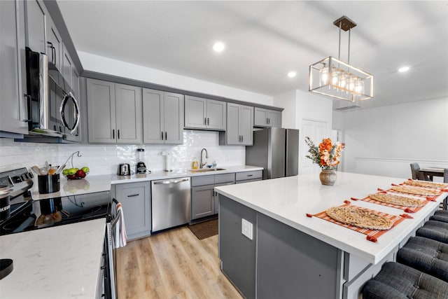5214 Sherman St, Houston, TX 77011 - kitchen with stainless steel appliances, gray cabinets, a breakfast bar, decorative backsplash, and a kitchen island
