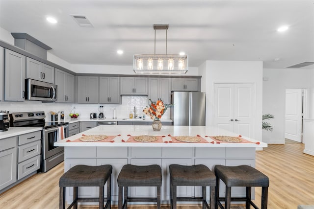 5214 Sherman St, Houston, TX 77011 - kitchen featuring stainless steel appliances, gray cabinetry, a breakfast bar, a kitchen island, and recessed lighting