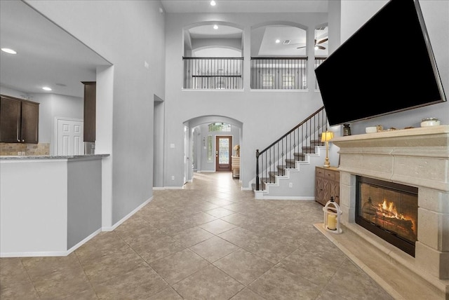 2424 Santiago Ln, League City, TX 77573 - foyer entrance with arched walkways, stairway, a high end fireplace, a ceiling fan, and a towering ceiling