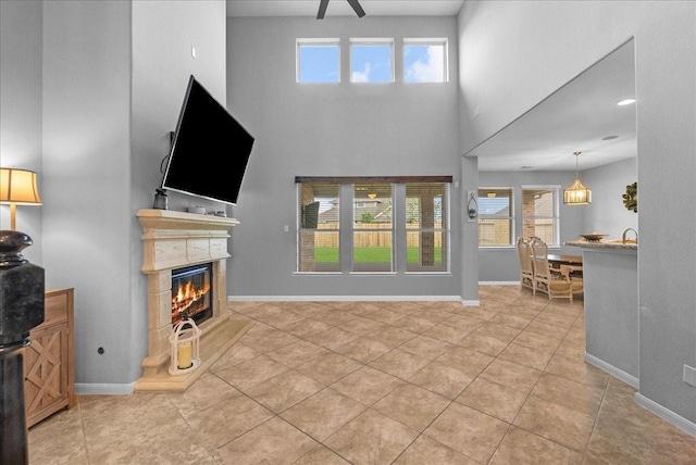 2424 Santiago Ln, League City, TX 77573 - tiled living area featuring a glass covered fireplace, healthy amount of natural light, a towering ceiling, and a ceiling fan