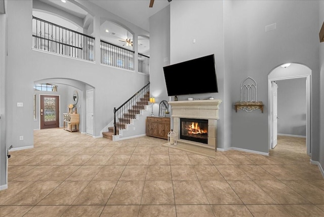 2424 Santiago Ln, League City, TX 77573 - unfurnished living room with a high ceiling, ceiling fan, a glass covered fireplace, stairs, and tile patterned floors