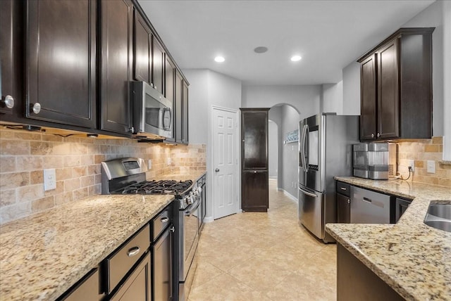 2424 Santiago Ln, League City, TX 77573 - kitchen featuring stainless steel appliances, arched walkways, light stone countertops, backsplash, and recessed lighting