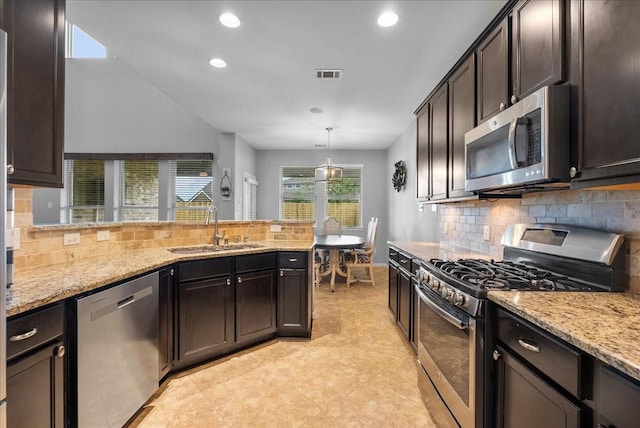 2424 Santiago Ln, League City, TX 77573 - kitchen featuring appliances with stainless steel finishes, tasteful backsplash, light stone countertops, recessed lighting, and a peninsula