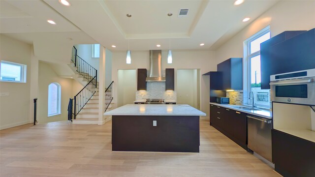 1844 Colquitt St, Houston, TX 77098 - kitchen featuring wall chimney range hood, stainless steel appliances, a kitchen island, a raised ceiling, and decorative backsplash